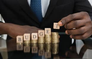 Businessman Putting The Letters Of The Word Budget On Coins